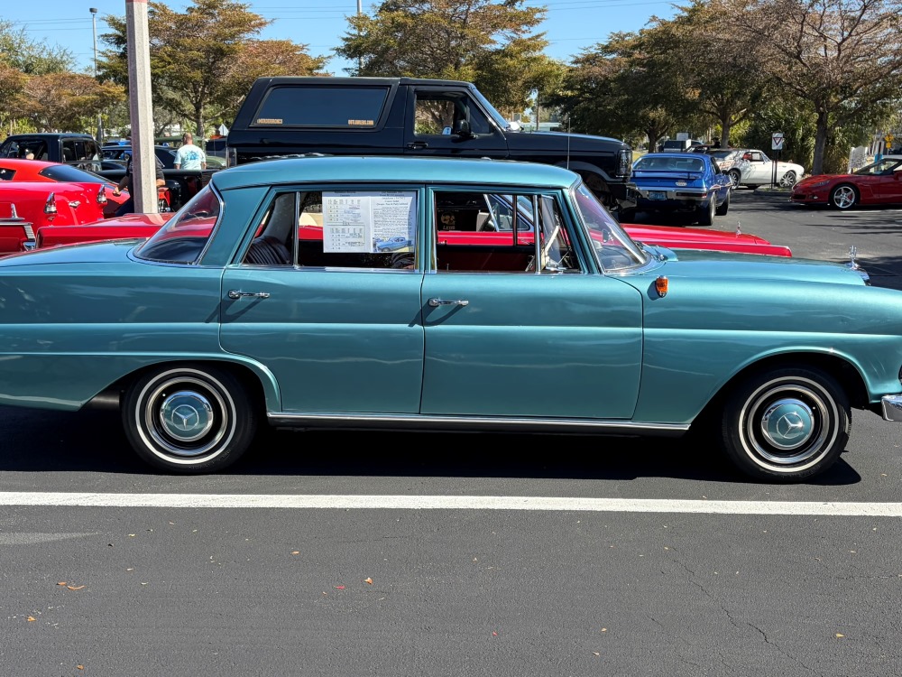 Side view of a teal vintage sedan parked at a sunny outdoor car show